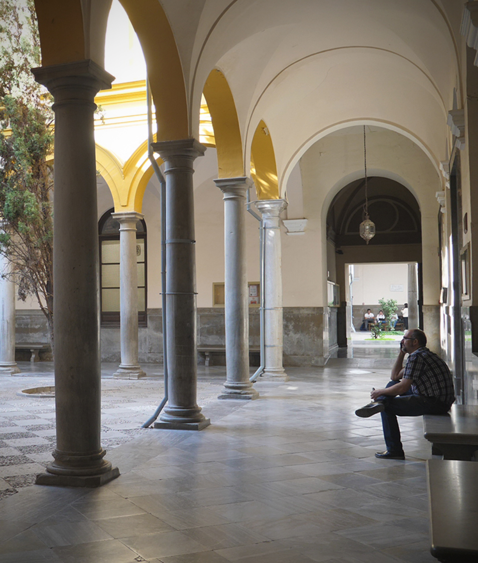 En uno de los pasillos que rodean el patio central de la Facultad de Derecho, un hombre descansa sentado en uno de los bancos disponibles