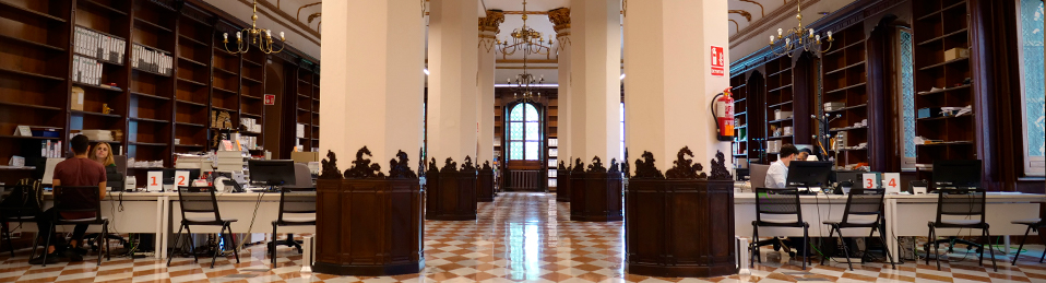 Amplia sala con seis grandes columnas donde se encuentras las mesas de la secretaría de la Facultad de Derecho