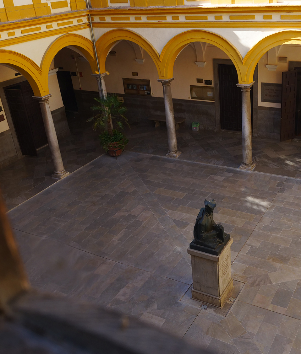 Patio interior de la Facultad de Derecho rodeado de arcos con columnas y un busto en el centro