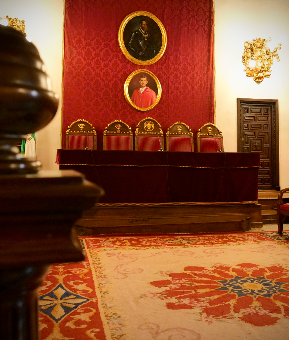 Salón de actos institucional de la Facultad de Derecho, vista cercana a la alfombra central y a las posiciones de honor, situadas bajo un retrato del rey Felipe VI