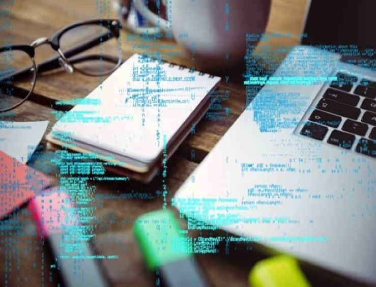 ciberseguridad mesa con libreta abierta con datos y portatil con codigos delante