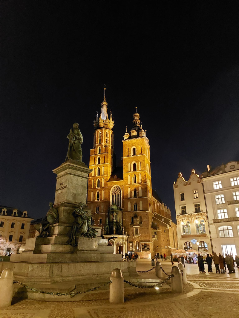 Cracovia. Plaza con una estatua en el centro y una iglesia al fondo con 2 torres muy altas.