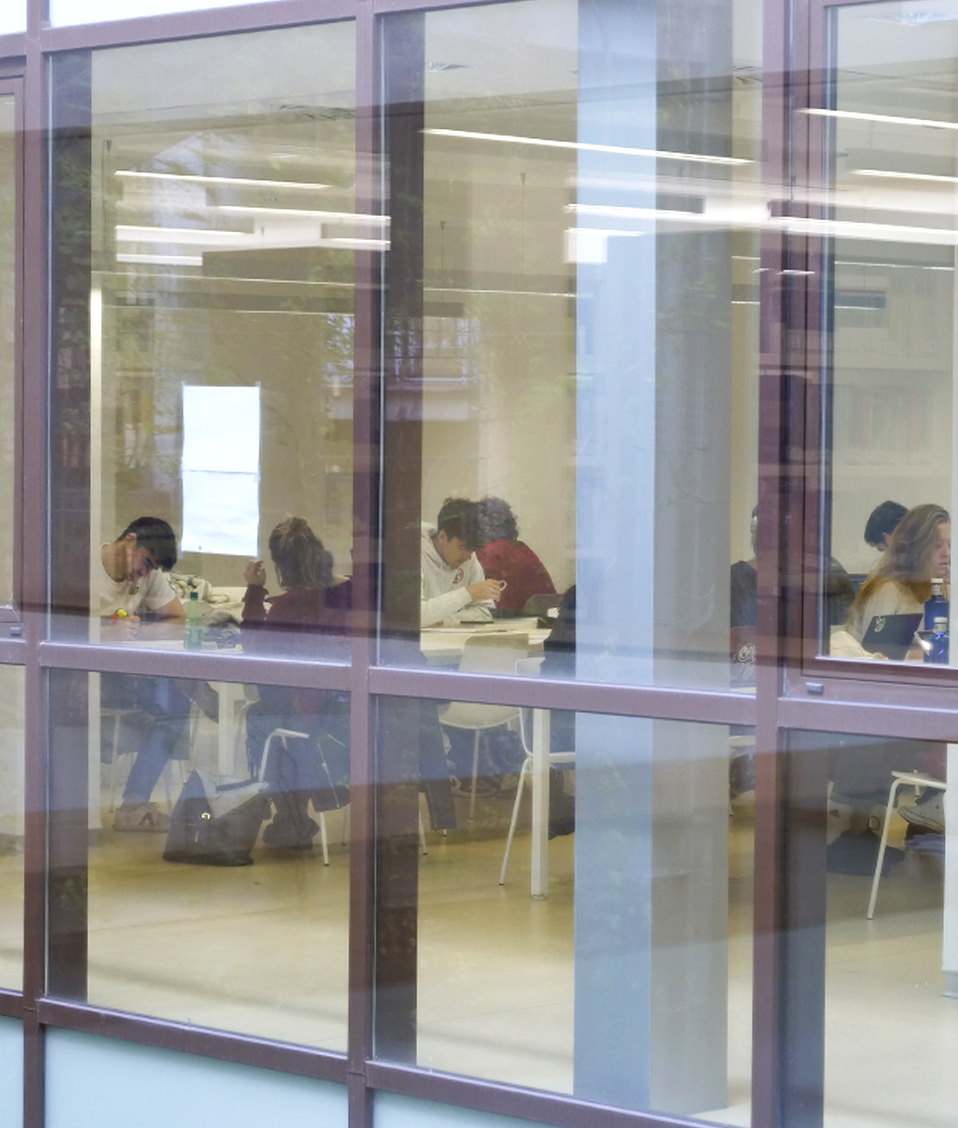Imagen de una de las zonas de estudio de la Biblioteca de la Facultad de Derecho, capturada a través de una ventana